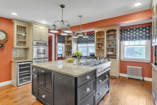 kitchen featuring beverage cooler, radiator, stainless steel appliances, and light wood-type flooring