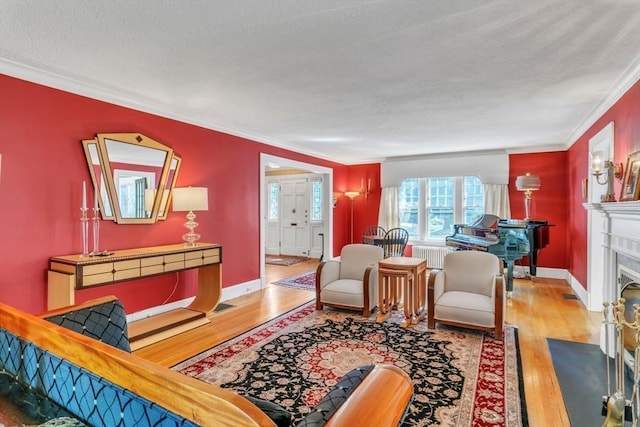 living room featuring a fireplace with flush hearth, a textured ceiling, wood finished floors, radiator heating unit, and crown molding