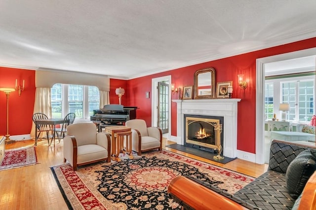 living area with hardwood / wood-style floors, baseboards, a lit fireplace, a textured ceiling, and crown molding