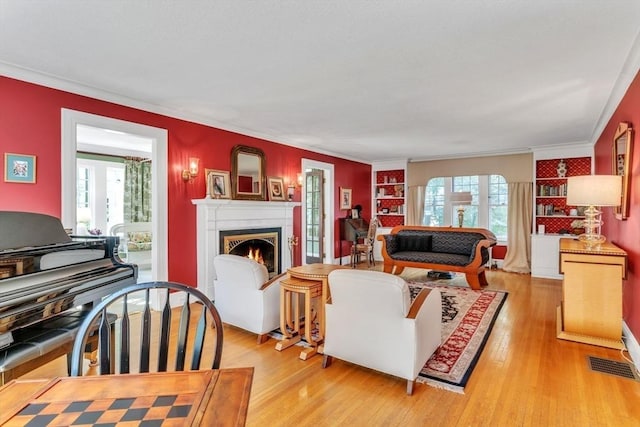 living area featuring light wood finished floors, visible vents, a wealth of natural light, and a lit fireplace