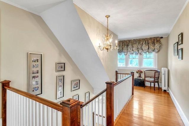 hallway featuring baseboards, an upstairs landing, light wood-style floors, and crown molding