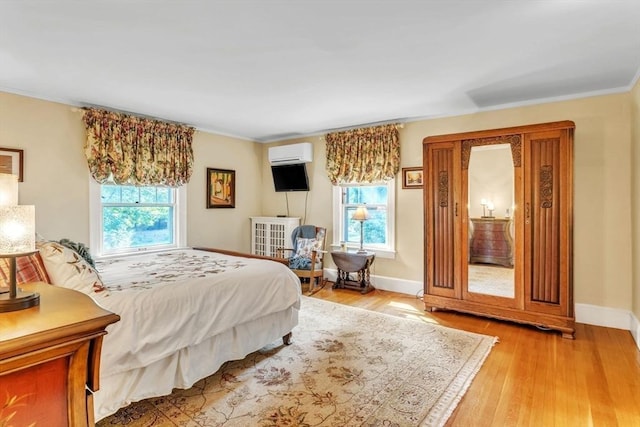 bedroom featuring light wood-type flooring, multiple windows, and a wall mounted AC