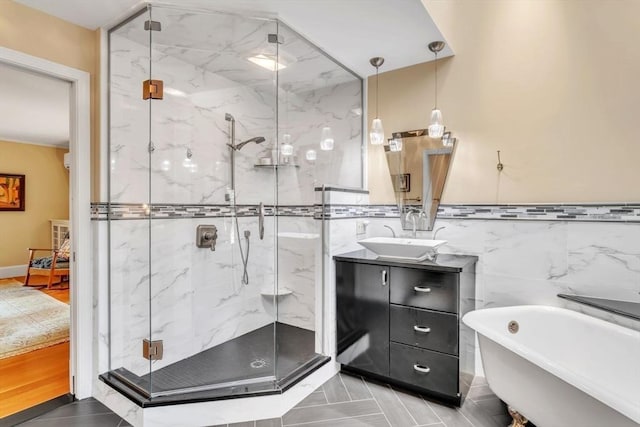 bathroom with vanity, tile walls, a marble finish shower, and a freestanding bath