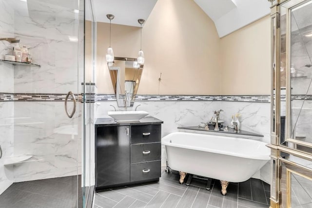 bathroom featuring a marble finish shower, a freestanding bath, vanity, and tile walls