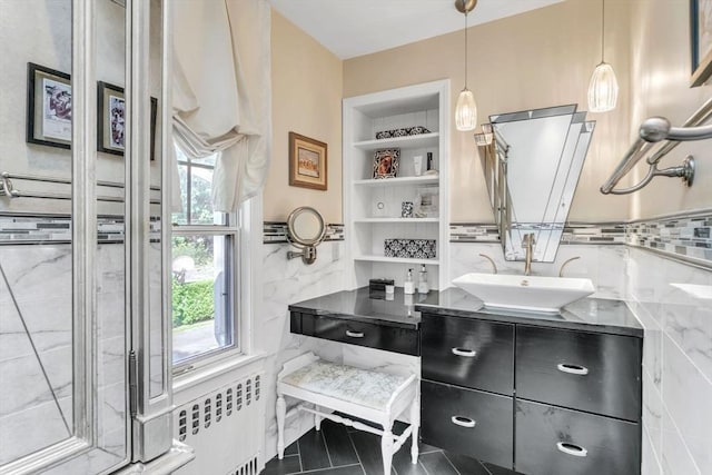 bathroom with a wainscoted wall, built in shelves, tile walls, and vanity