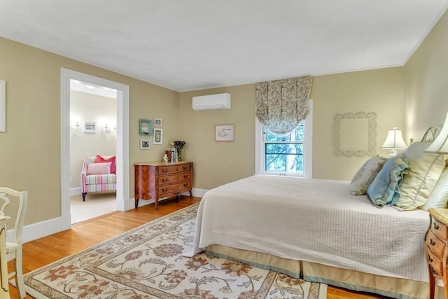 bedroom with baseboards, an AC wall unit, and wood finished floors