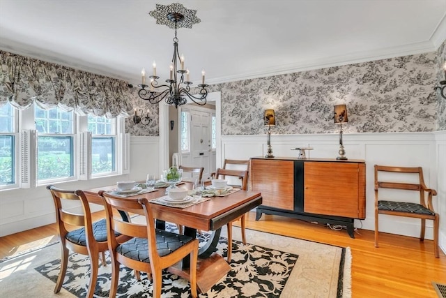 dining space featuring wainscoting, wallpapered walls, light wood-style flooring, and ornamental molding