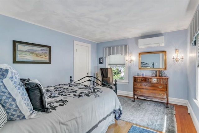 bedroom with baseboards, an AC wall unit, light wood-style floors, and ornamental molding