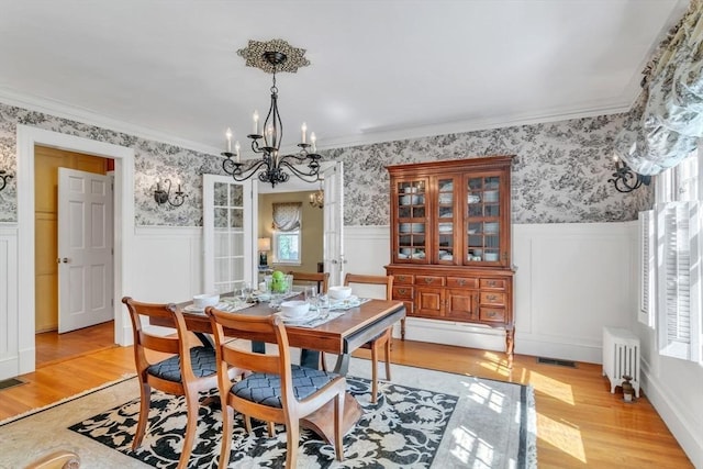 dining space featuring radiator, wainscoting, and wallpapered walls