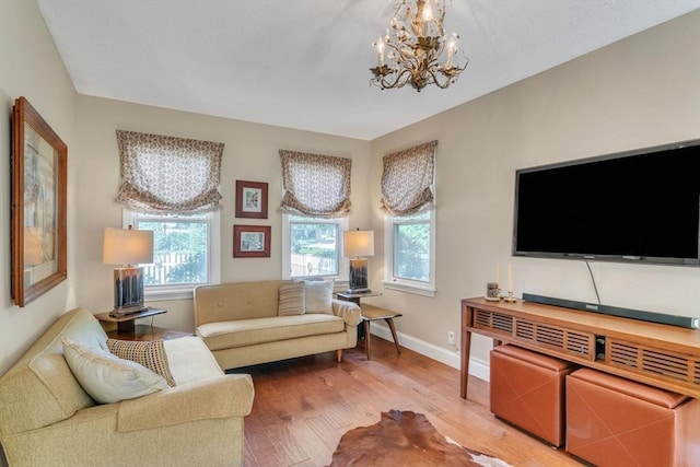 living area with wood finished floors, baseboards, and a chandelier