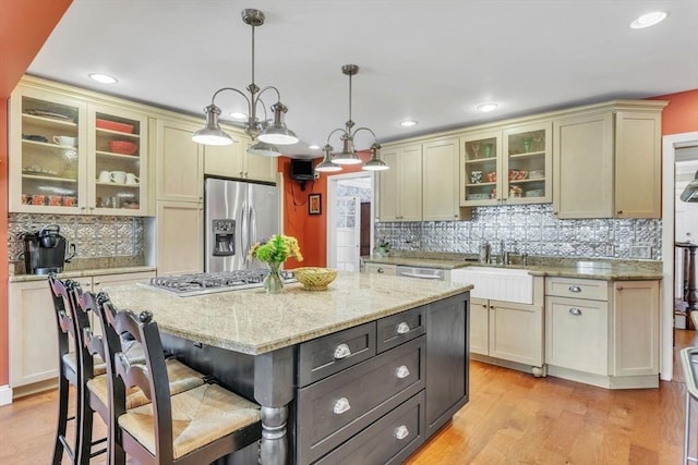 kitchen with a kitchen island, a kitchen bar, light wood-style flooring, hanging light fixtures, and stainless steel appliances