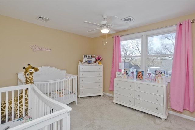 bedroom with ceiling fan, light colored carpet, and a crib