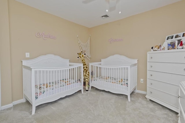 bedroom with a crib, light colored carpet, and ceiling fan