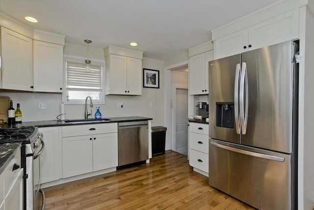 kitchen with pendant lighting, stainless steel appliances, sink, and white cabinets