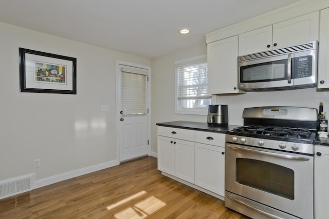 kitchen with white cabinetry, stainless steel appliances, and light wood-type flooring