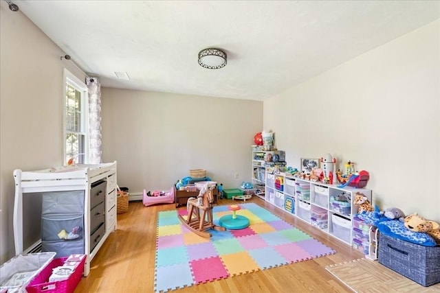 playroom featuring wood finished floors and a baseboard heating unit