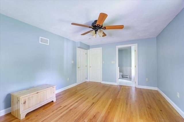 unfurnished bedroom featuring baseboards, light wood-style flooring, ensuite bath, and a baseboard radiator