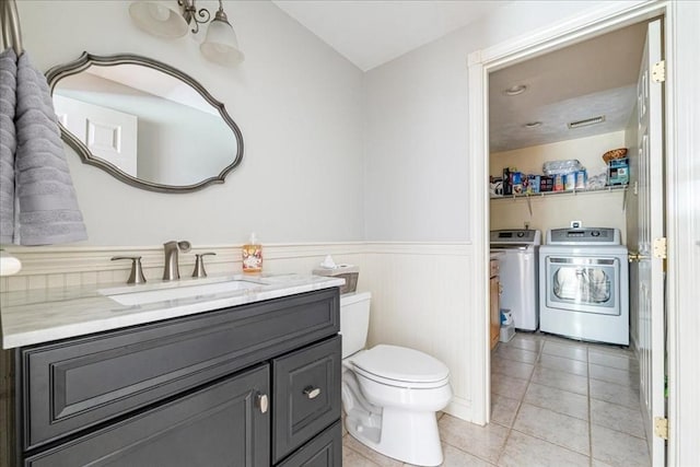bathroom with washer and clothes dryer, wainscoting, tile patterned floors, vanity, and toilet