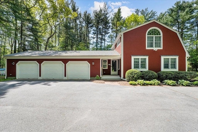 dutch colonial featuring asphalt driveway and an attached garage