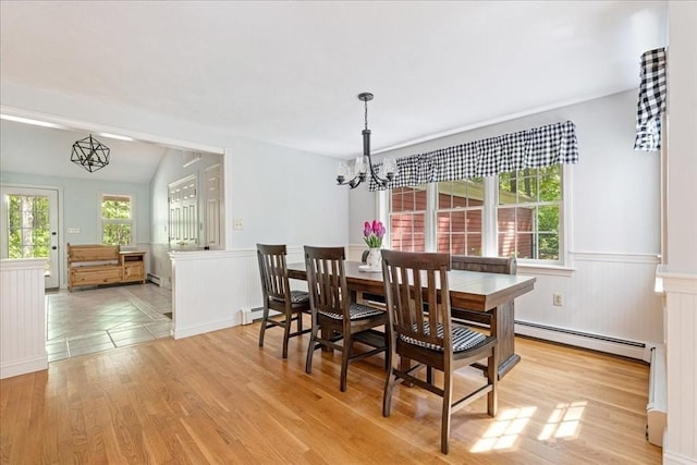 dining space with a baseboard radiator, a wainscoted wall, a chandelier, light wood-style floors, and a baseboard heating unit