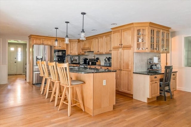 kitchen featuring stainless steel fridge with ice dispenser, black microwave, a kitchen breakfast bar, and light wood finished floors