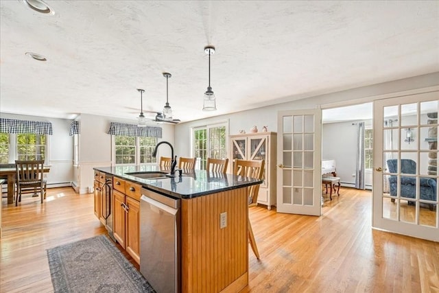 kitchen featuring a sink, dishwasher, french doors, brown cabinets, and light wood-type flooring