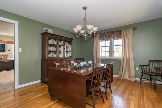 dining room with an inviting chandelier, baseboards, light wood-type flooring, and visible vents