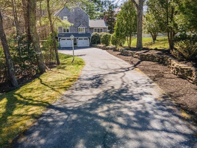 view of front facade featuring an attached garage, driveway, and a chimney