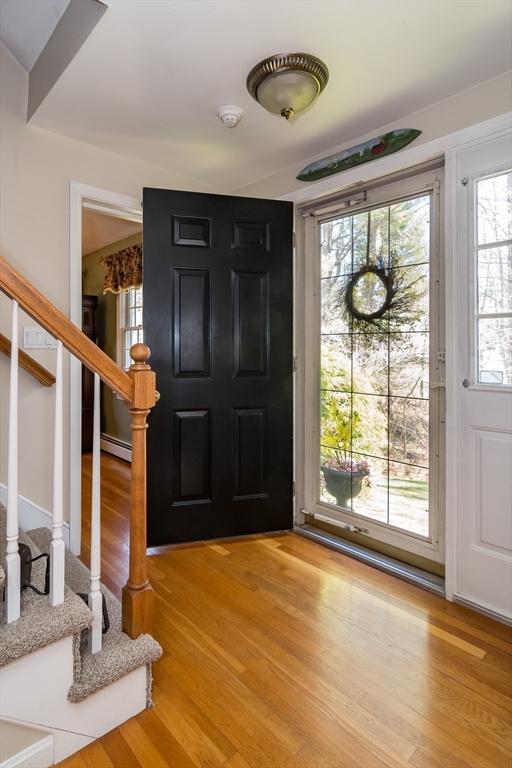 foyer with stairway, light wood finished floors, and a baseboard radiator