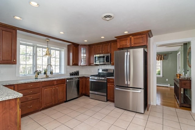 kitchen featuring a sink, tasteful backsplash, baseboard heating, and stainless steel appliances