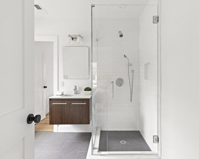 bathroom featuring a shower with shower door, vanity, and tile patterned flooring