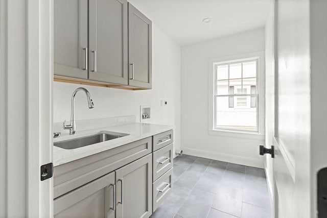 kitchen featuring light tile patterned floors, light stone counters, sink, and gray cabinetry