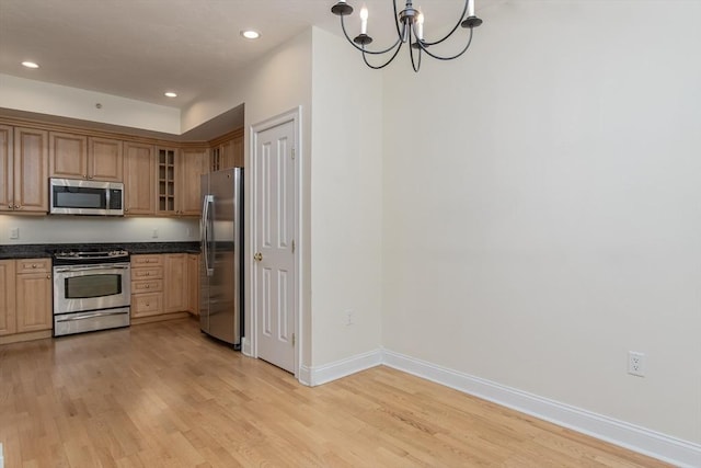 kitchen with appliances with stainless steel finishes, pendant lighting, an inviting chandelier, and light hardwood / wood-style flooring