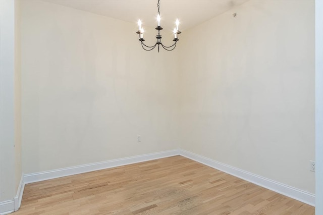 unfurnished room featuring a notable chandelier and light hardwood / wood-style flooring