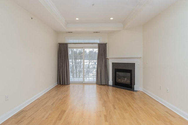 unfurnished living room with ornamental molding, light hardwood / wood-style floors, and a raised ceiling