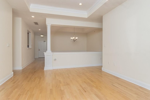 spare room with decorative columns, crown molding, and light wood-type flooring