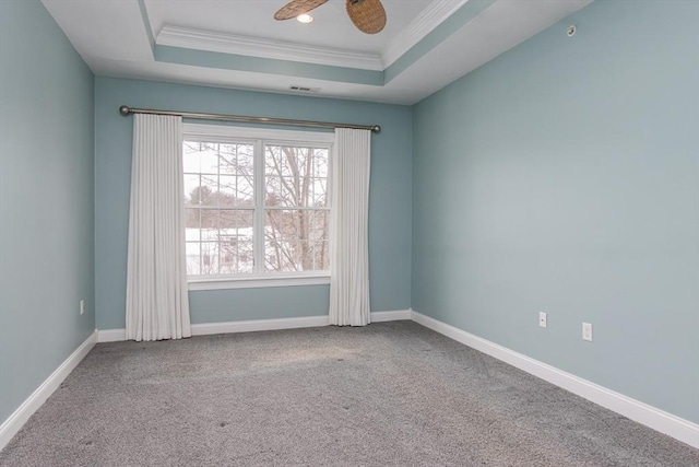 carpeted empty room featuring ornamental molding, ceiling fan, and a tray ceiling