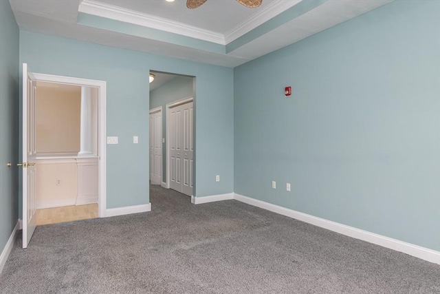 unfurnished bedroom featuring crown molding, a raised ceiling, and carpet