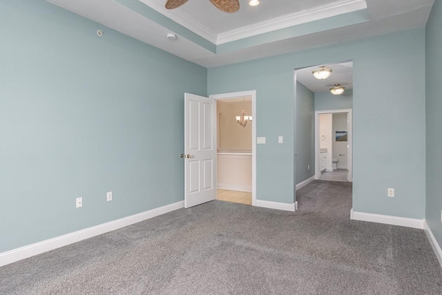 carpeted empty room featuring a tray ceiling, ornamental molding, and ceiling fan