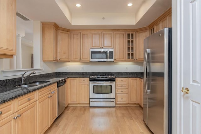 kitchen featuring sink, light hardwood / wood-style flooring, dark stone countertops, stainless steel appliances, and light brown cabinetry