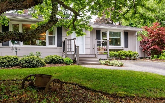 ranch-style home with board and batten siding, a chimney, and a front yard