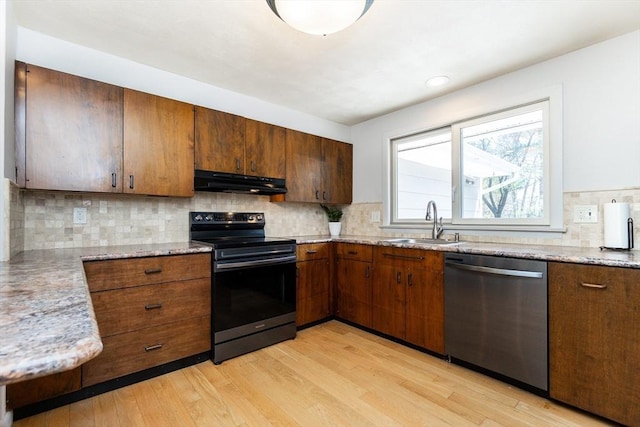 kitchen featuring a sink, light wood-style floors, stainless steel dishwasher, under cabinet range hood, and range with electric stovetop