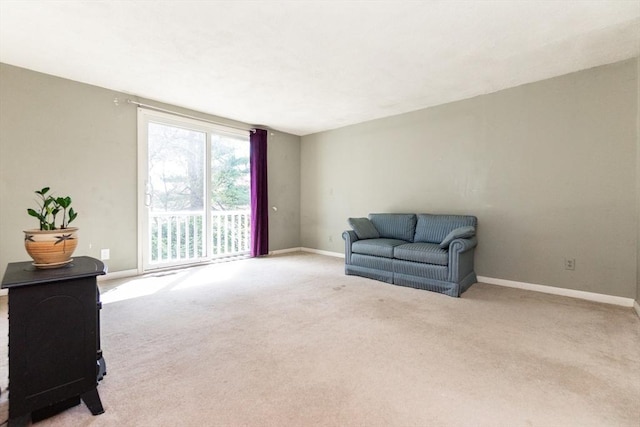 living area featuring baseboards, a wood stove, and carpet flooring
