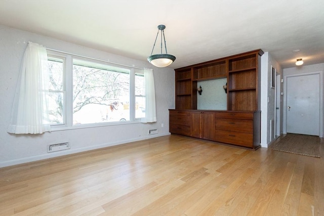 unfurnished dining area featuring baseboards and light wood finished floors