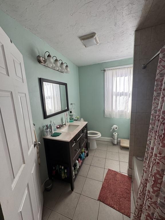 bathroom with toilet, a textured ceiling, tile patterned flooring, baseboards, and vanity