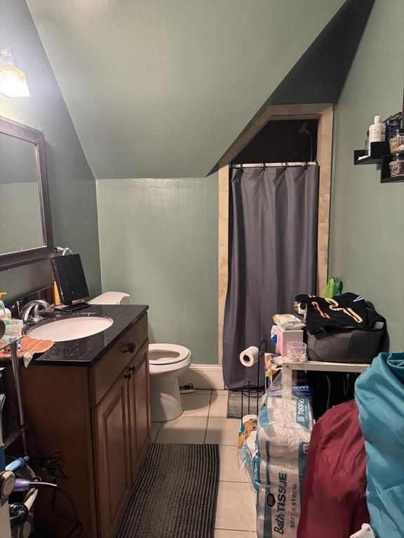 full bathroom featuring toilet, a shower with shower curtain, vaulted ceiling, tile patterned floors, and vanity