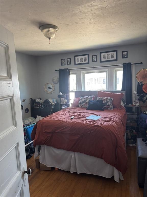 bedroom with a textured ceiling and wood finished floors