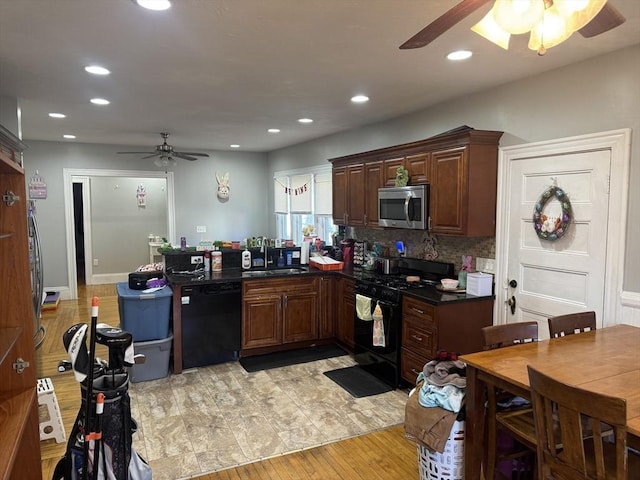 kitchen with dark countertops, decorative backsplash, a peninsula, black appliances, and a sink