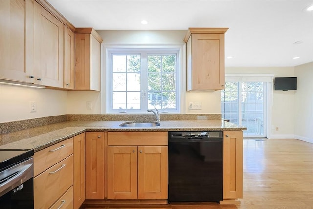 kitchen with black dishwasher, sink, light stone counters, light brown cabinets, and light wood-type flooring