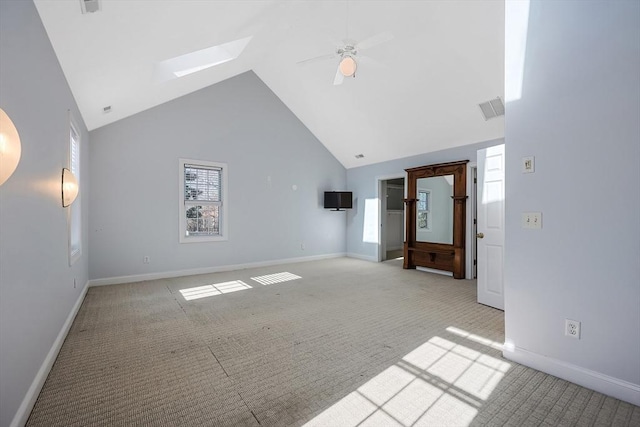 unfurnished living room featuring ceiling fan, light colored carpet, a skylight, and high vaulted ceiling